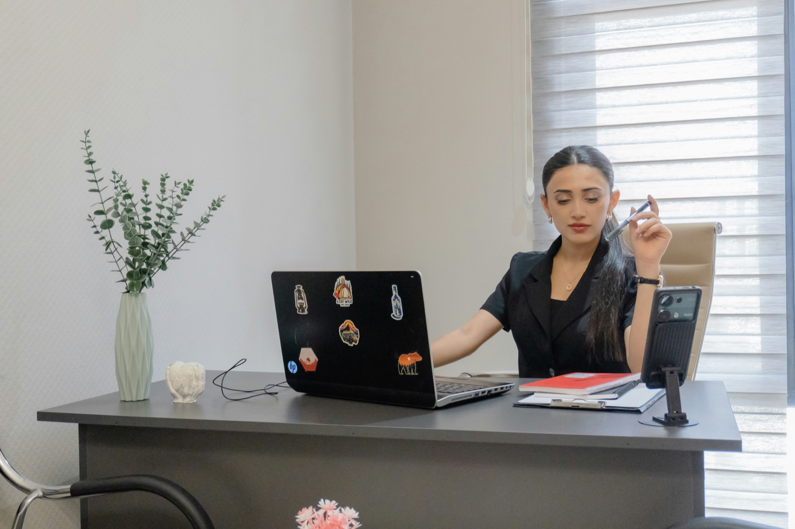 A nurse working from a home desk with a laptop and phone