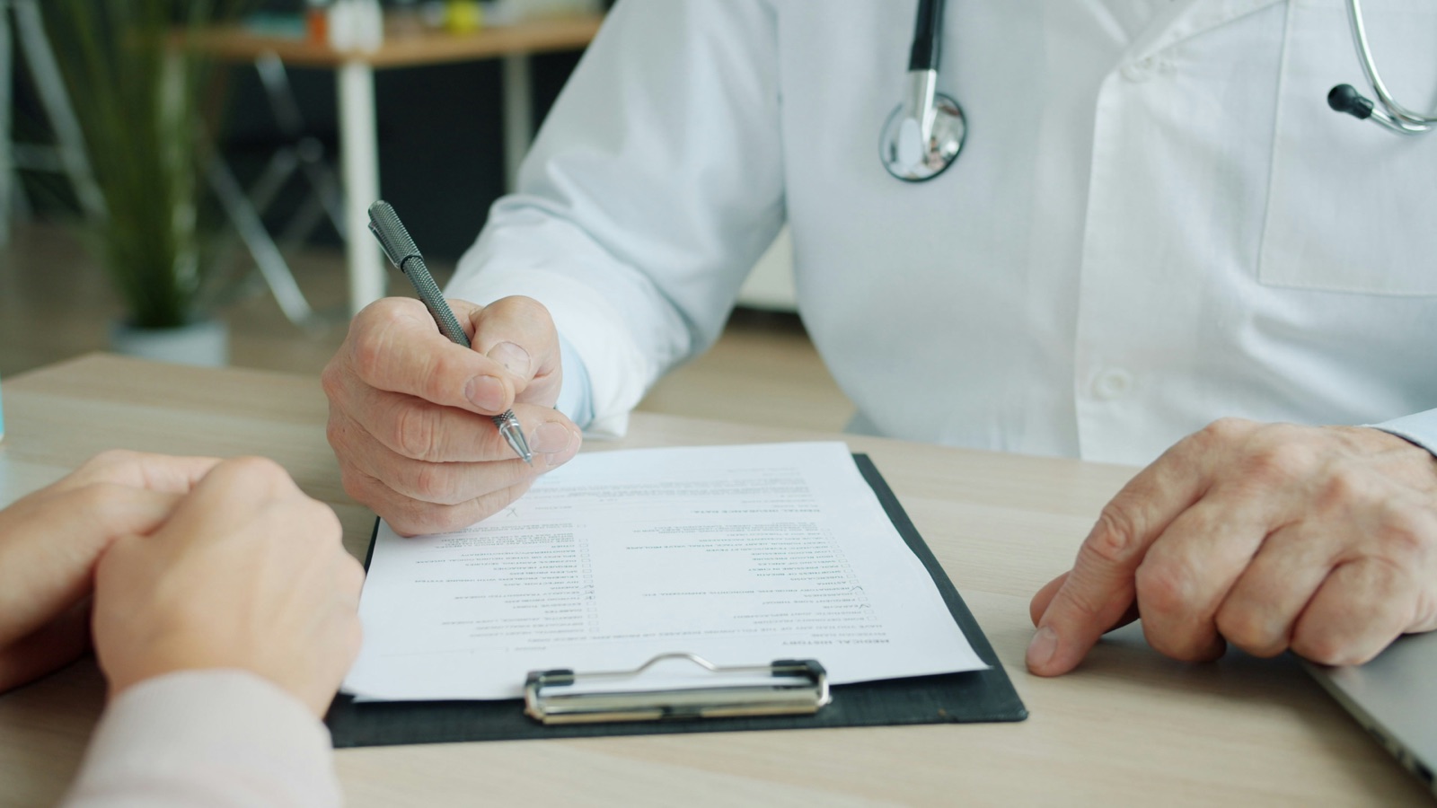 A nurse writing clinical documentation on a patient chart
